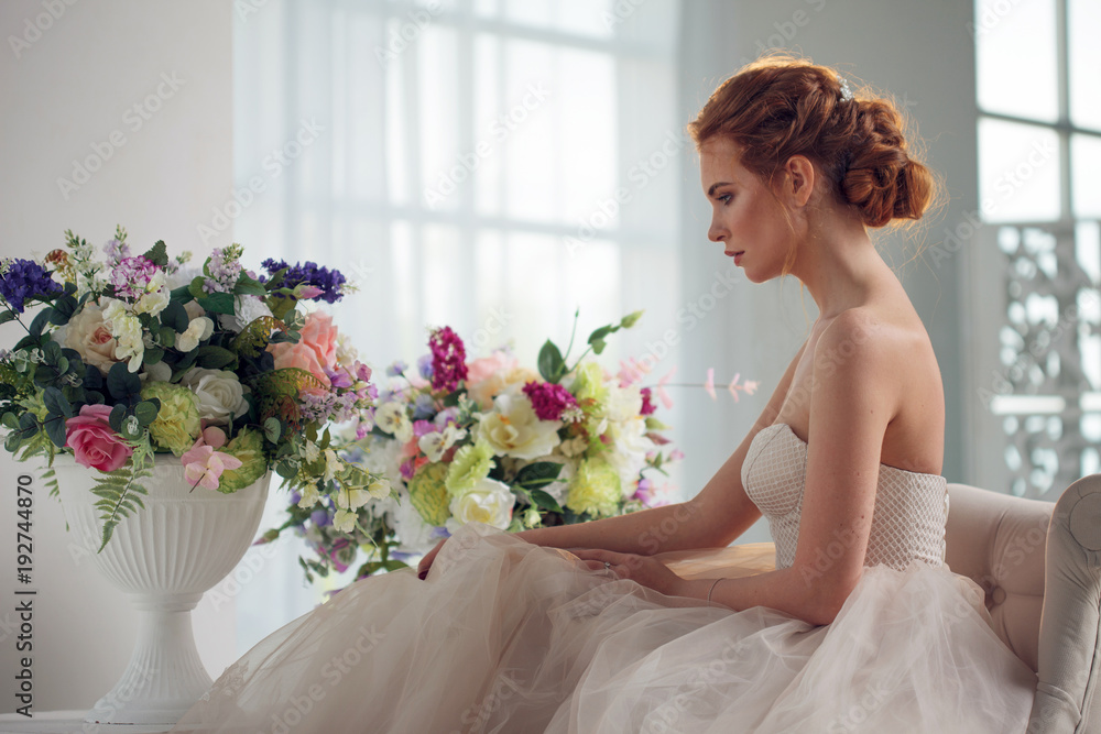 Portrait of a beautiful girl in a wedding dress. Bride in luxurious dress sitting on a chair