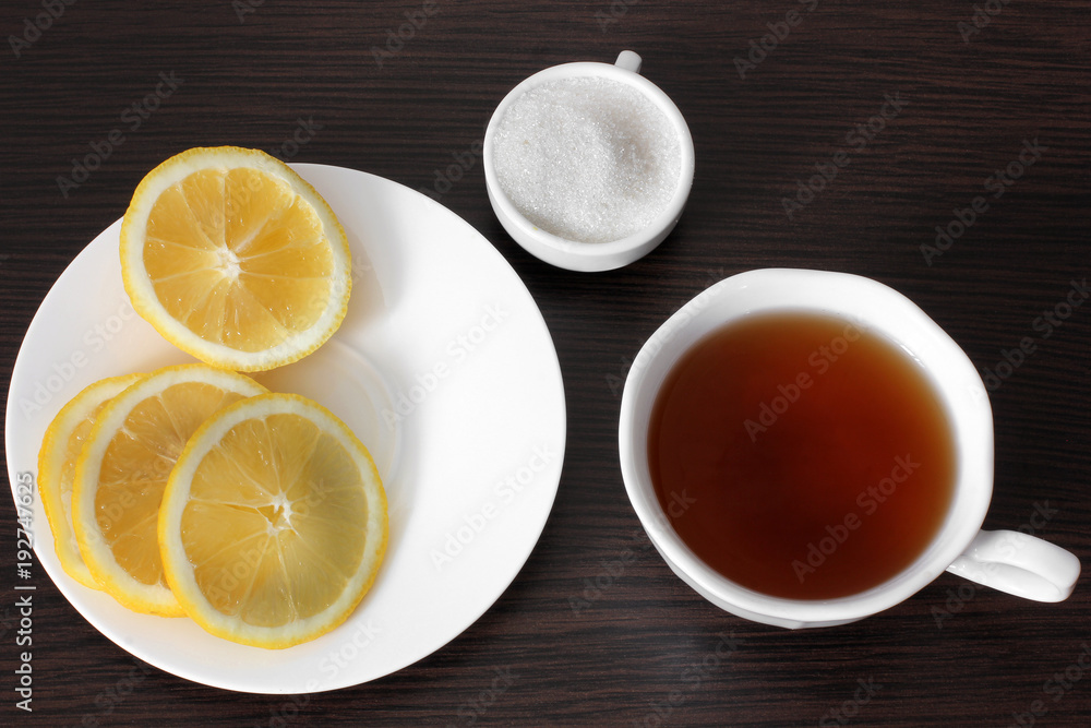 Tea with lemon on a wooden background. Tea, lemon and sugar. Tea with lemon on a wooden background. Tea, lemon and sugar.