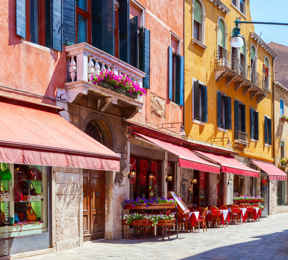 Colorful street with tables of cafe at a sunny morning, Venice, Italy.