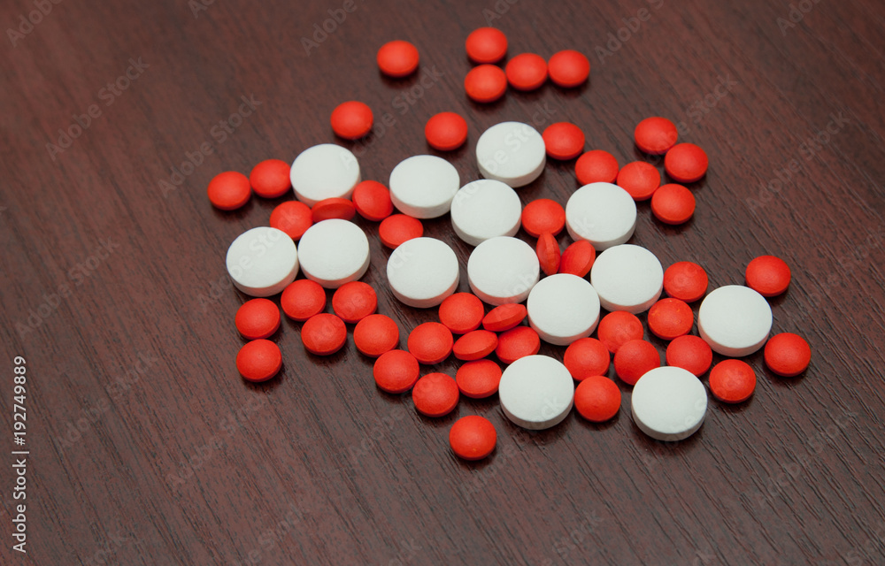 Composition by CU from large red and white pills spilled on a table. Composition by CU from large red and white pills spilled on a table.