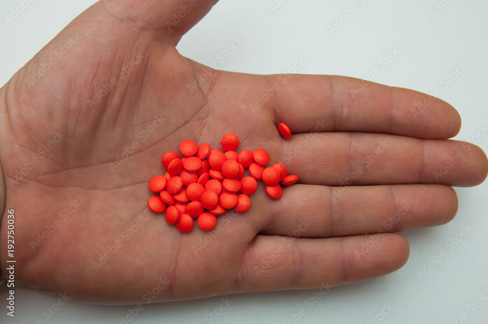 Large red pills are decomposed on the hand of man. Large red pills are decomposed on the hand of man.