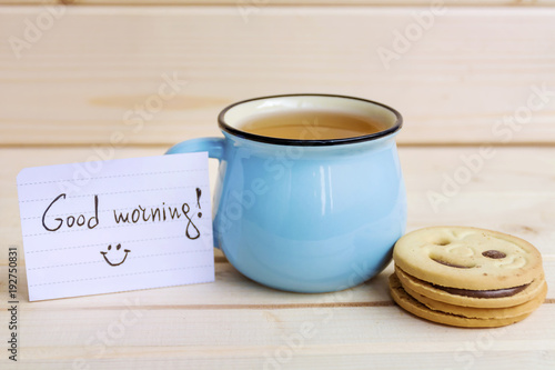 blue mug of tea and oatmeal cookies on wooden background