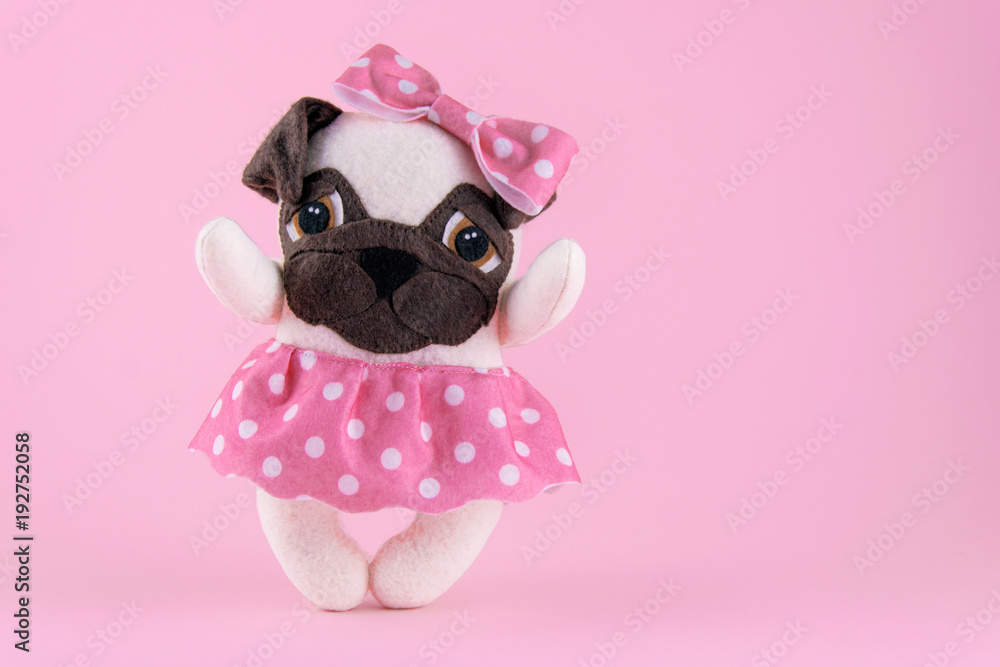 Handmade toy dog of pug breed on a pink background.Toned. Handmade toy dog of pug breed on a pink background.Toned.
