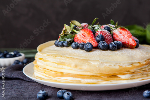 Crepes cake with cottage cheese and strawberry, selective focus on wood table.