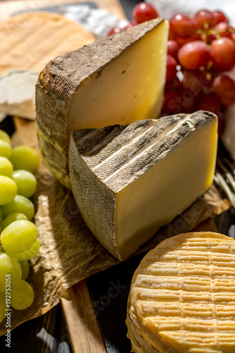 Tasting of oldest french AOC soft pudgent yellow cheese Livarot,  Munster and semifirm Tomme french cheeses photo