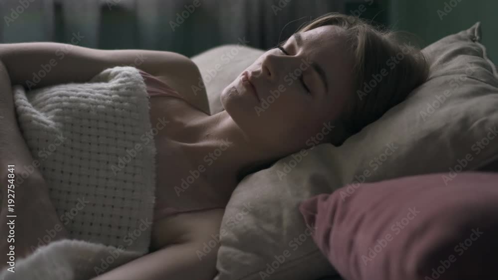 Pretty young woman sleeping in bed under blanket Pretty young woman sleeping in bed under blanket