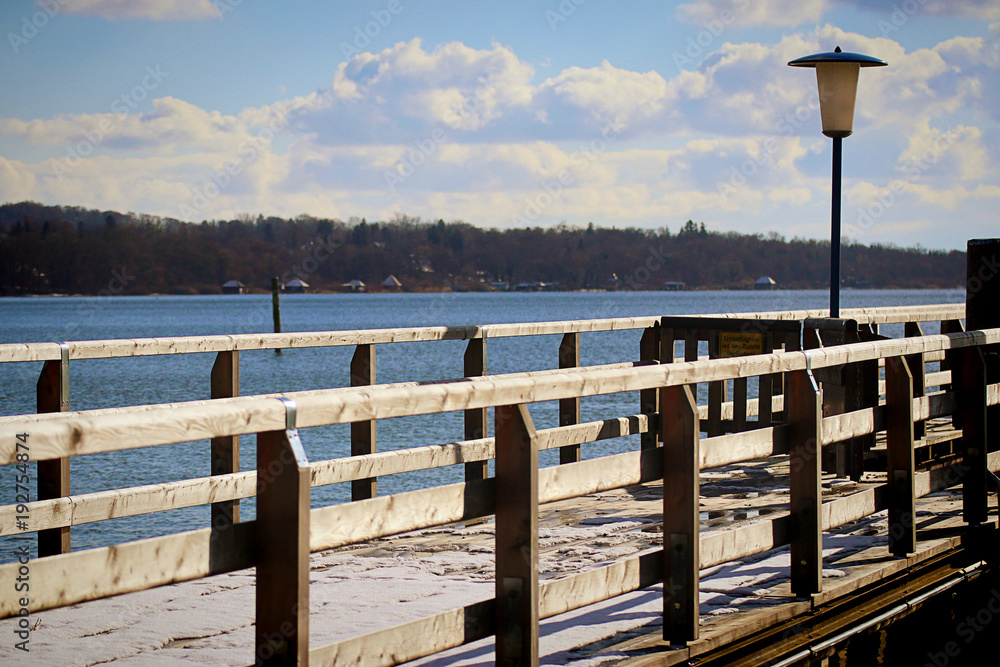 Ammersee bavarian lake near Munich, winter view of the waterfront at Stegen village, with wooden pier and blue waters