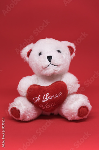 Weißer Teddybär mit roten Ich liebe Dich Herz auf roten Hintergrund