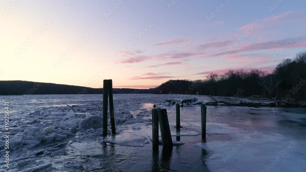 Theatrical drone shot of frozen river in the wilderness at dusk in winter Theatrical drone shot of frozen river in the wilderness at dusk in winter