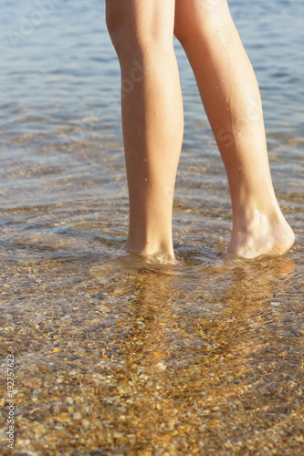 Feet in the crystal clear sea water. The bottom with the shell