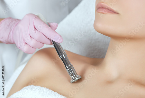 The cosmetologist makes the procedure Microdermabrasion of the decollete skin of a beautiful, young woman in a beauty salon.Cosmetology and professional skin care.