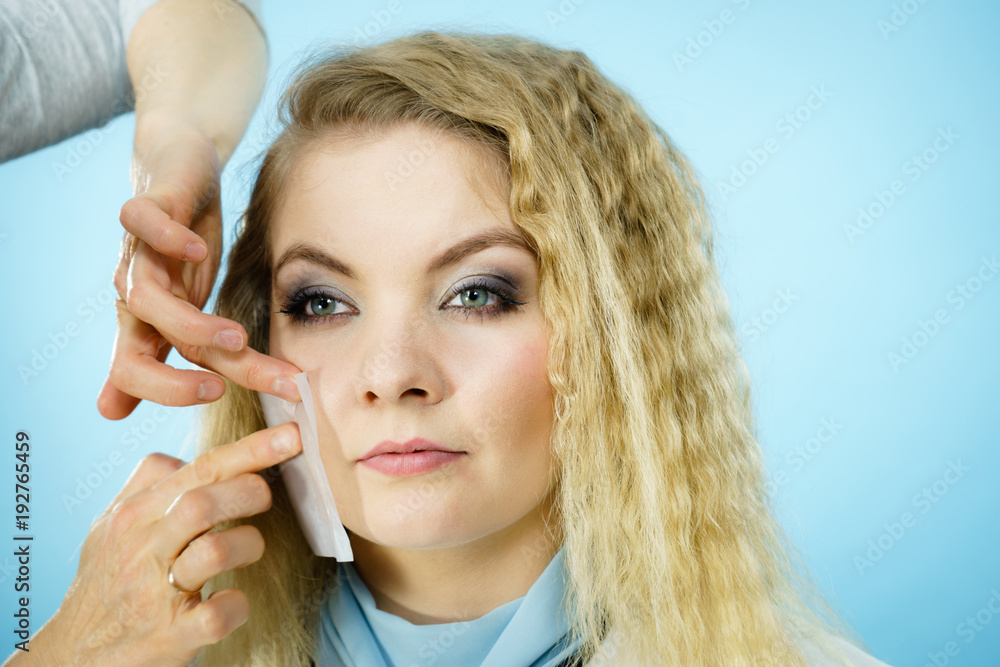 Fototapeta premium Woman using oil blotting tissues on model