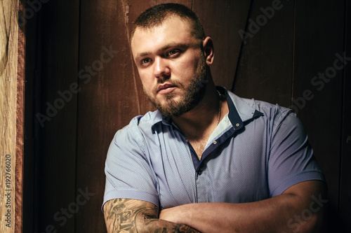 Εκτύπωση καμβά brutal bearded man with a tattoo on his arm, a portrait of a man in dramatic lig