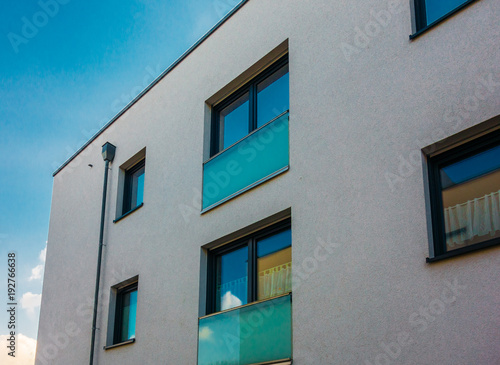 white big apartment facade with green glass windows