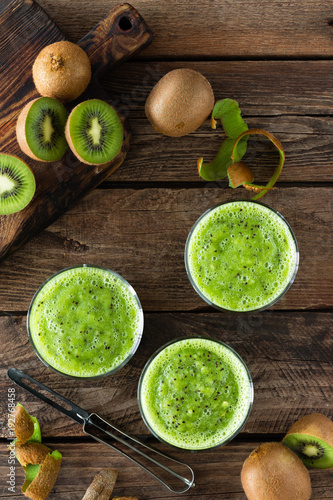 Kiwi smoothie drink of spinach leaves and fresh fruits on wooden rustic table, healthy detox diet