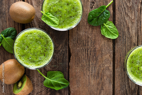 Kiwi smoothie drink of spinach leaves and fresh fruits on wooden rustic table, healthy detox diet
