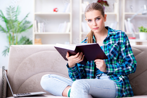 Female student reading the book sitting on the sofa