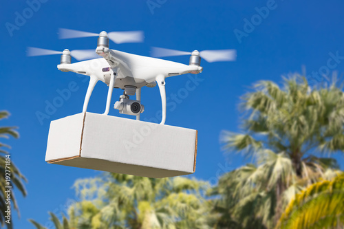 Unmanned Aircraft System (UAV) Quadcopter Drone Carrying Blank Package Over Tropical Terrain.
