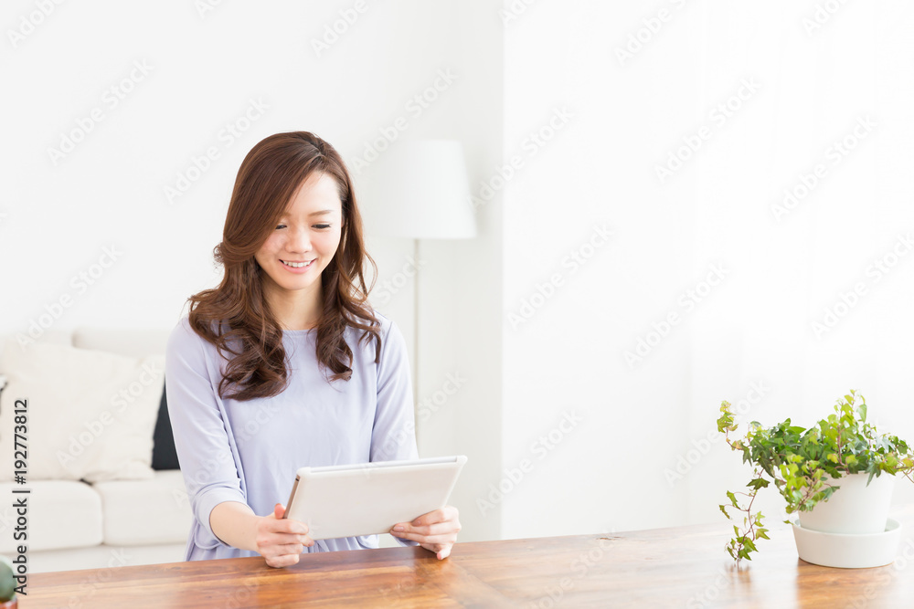 部屋でタブレットを見る女性 部屋でタブレットを見る女性