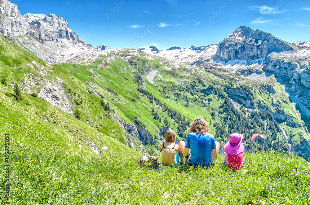 young people sitting on a meadow surrounded by Swiss nature and mountain scenery