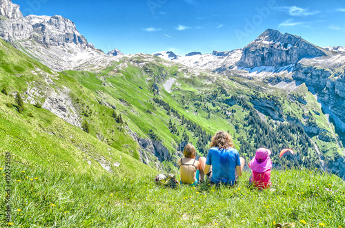 young people sitting on a meadow surrounded by Swiss nature and mountain scenery
