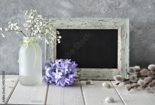 Spring flowers and a blackboard on white table, sprngtime background, space photo