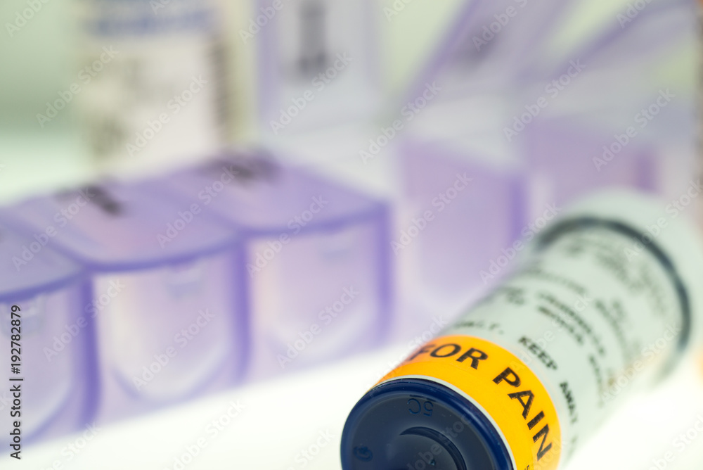 horizontal image of prescription pain medication bottles and weekly pill organizer. shallow depth of field with room for copy. 