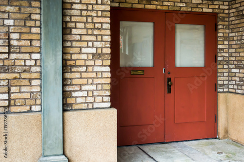 The red wooden door with glass and old brick