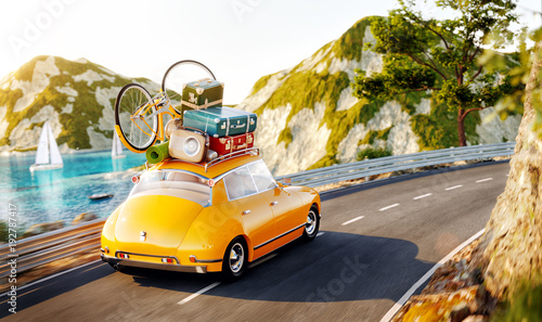 Cute little retro car with suitcases and bicycle on top goes by the road alon...