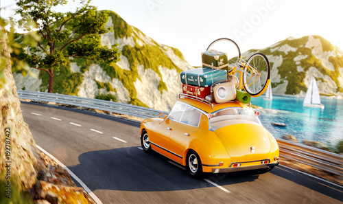 Cute little retro car with suitcases and bicycle on top goes by the road alon...