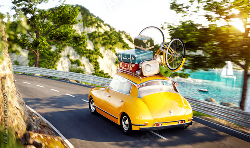 Cute little retro car with suitcases and bicycle on top goes by the road alon...