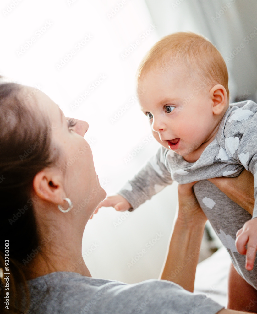 Happy smiling mother and baby playing on bed at home. Happy family having fun. Happy smiling mother and baby playing on bed at home. Happy family having fun.