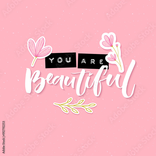 You are beautiful. Inspirational quote with embossed metal letters and modern brush calligraphy decorated with hand drawn flowers on pink background. Trendy collage for social media and apparel.