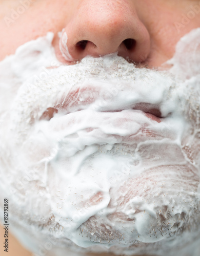 A man is applying face shaving foam