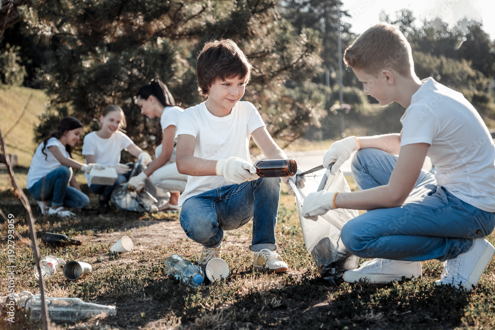 Our environment. Nice positive young boys looking at each other and working together while collecting rubbish Our environment. Nice positive young boys looking at each other and working together while collecting rubbish
