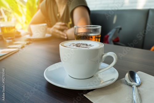 Coffee cup in coffee shop with woman blur background.