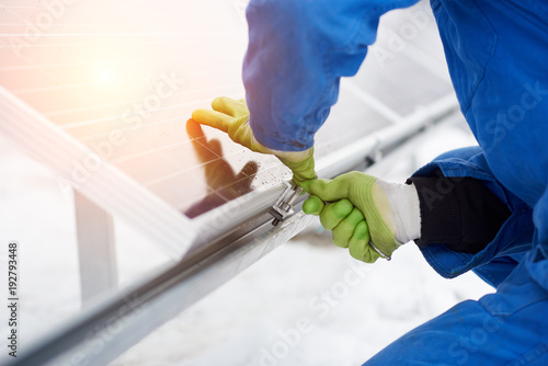 Engineers installing solar panels. Worker with tools maintaining photovoltaic panels in snow-covered weather. Macro photography. photo