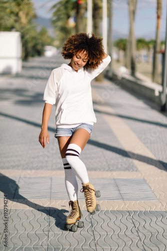 Black woman on roller skates rollerblading in beach promenade with palm trees