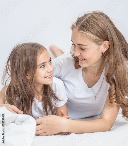 Happy mother hugs her daughter on the bed