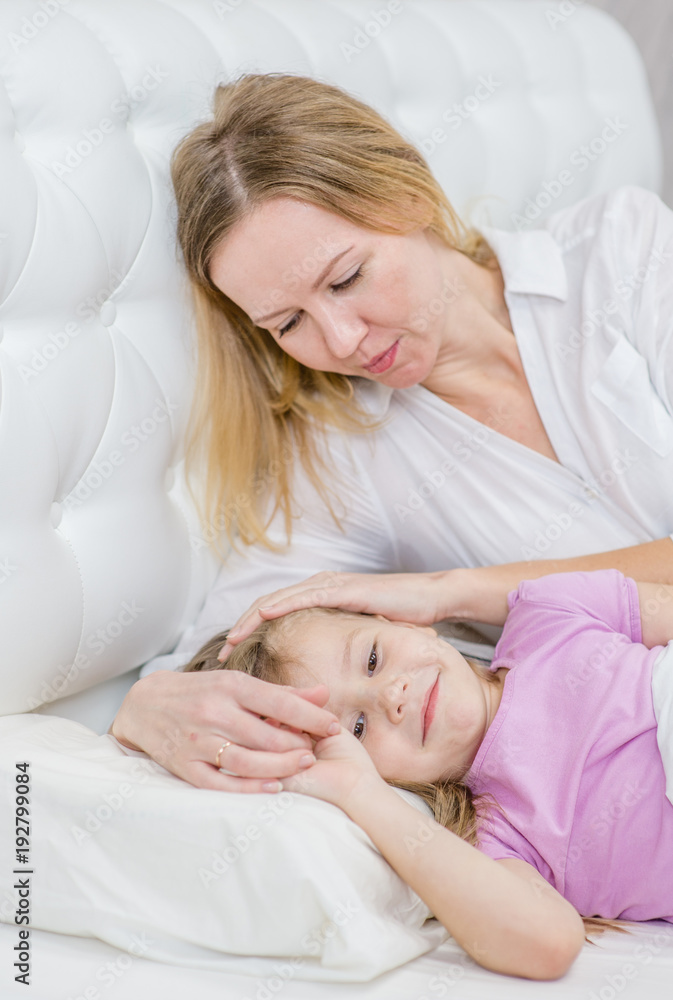 Mother lying with her little daughter on the bed Mother lying with her little daughter on the bed