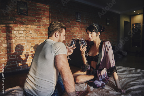 Strong Man and beautiful woman lying on the bed intimate atmosphere. Luxurious furniture and beautiful interior. A girl with black hair is a man without a shirt. Love and tenderness.