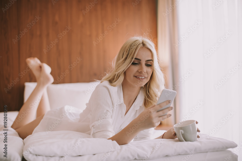 Pretty young woman with mobile phone in the bed Pretty young woman with mobile phone in the bed