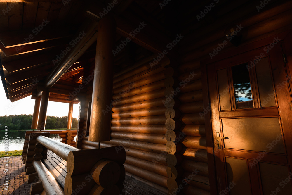 Modern russian village in national russian style on the lake coast. Good place for camping, fishing, hunting and relax. Summer sunset sky reflection in calm warm water. Modern russian village in national russian style on the lake coast. Good place for camping, fishing, hunting and relax. Summer sunset sky reflection in calm warm water.