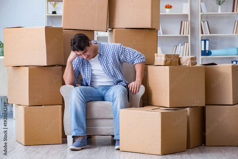 Young man moving in to new house with boxes Young man moving in to new house with boxes