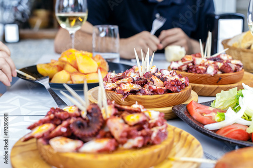 People eating Pulpo a la Gallega with potatoes. Galician octopus dishes. Famous dishes from Galicia, Spain. photo