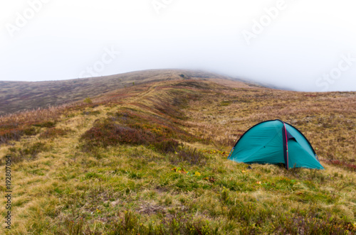 Tourist tent in the mountains. Mountains in the clouds. Top in the clouds. Morning fog.