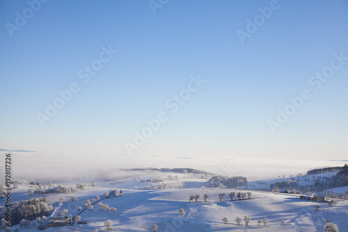 snowy hilly winter landscape with foggy sky