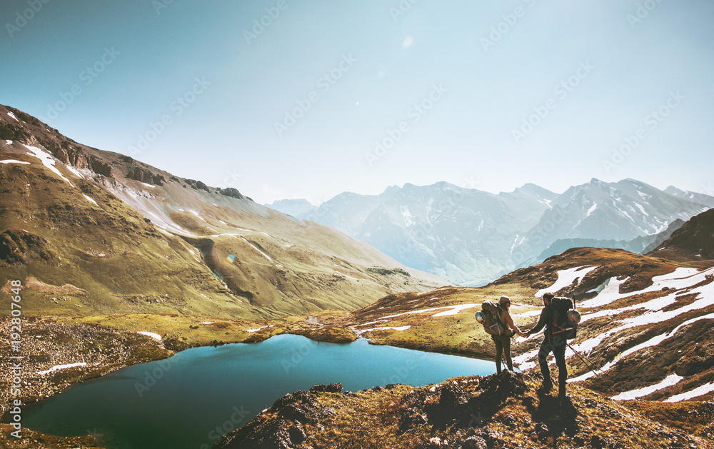 Couple travelers holding hands on mountain cliff over lake together love and Travel Lifestyle wanderlust concept adventure vacations outdoor aerial view. - obrazy, fototapety, plakaty 