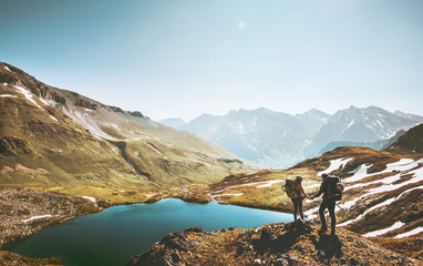 Couple travelers holding hands on mountain cliff over lake together love and Travel Lifestyle wanderlust concept adventure vacations outdoor aerial view.