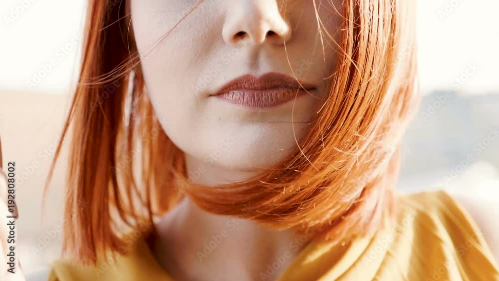 The wind is blowing a redhead woman hair in slow motion at the sunset. Close up footage The wind is blowing a redhead woman hair in slow motion at the sunset. Close up footage